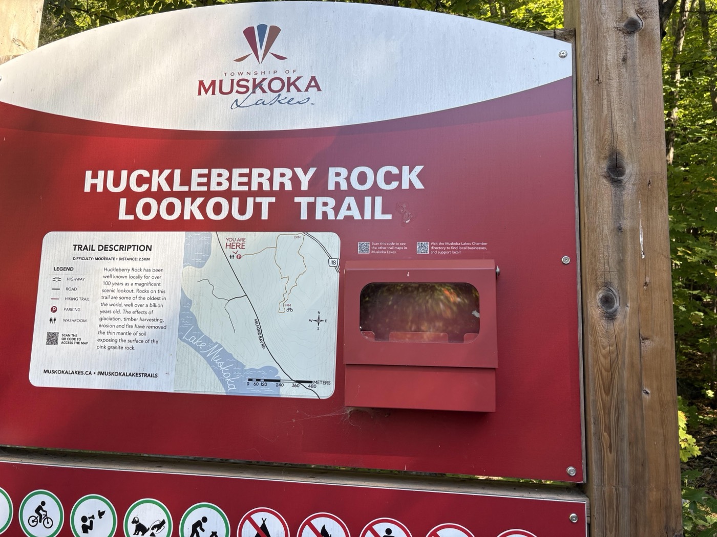 A trailhead information board for the Huckleberry Rock Lookout Trail, showing a small map, a legend and a short trail description.